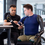 Engineer adjusting arm band on man in wheelchair